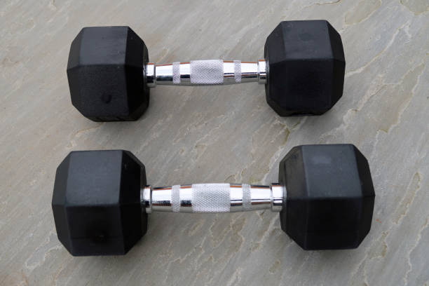 istock Pair of hexagonal dumbbells on a light grey slate surface outdoors 1307381201