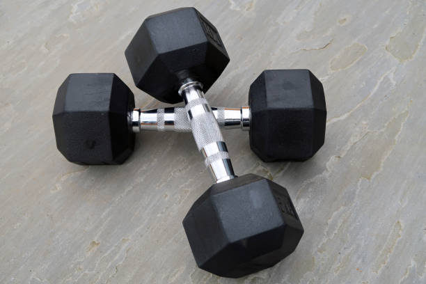 istock Pair of hexagonal dumbbells on a light grey slate surface outdoors 1307381203