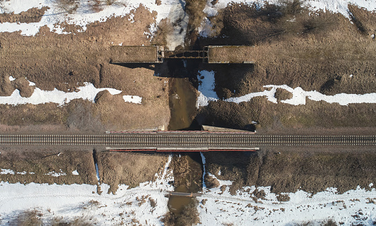 Railroad bridge over small river above drone top view