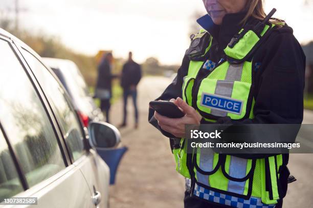 Oficial De Policía De Tránsito Registrando Detalles Del Accidente De Tráfico En El Teléfono Móvil Foto de stock y más banco de imágenes de Cuerpo de policía