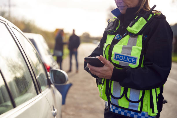 여성 교통 경찰관은 휴대 전화에 도로 교통 사고의 세부 사항을 기록 - 영국 뉴스 사진 이미지