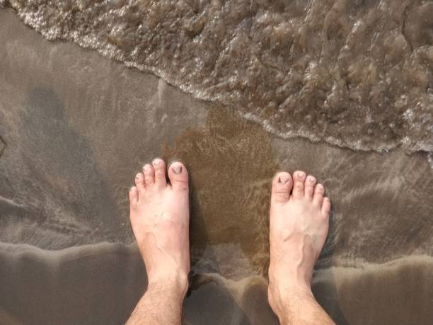 Low section of legs on shore at beach during vacation