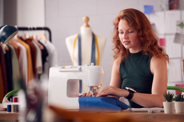 istock Female Student Or Business Owner Working In Fashion Using Sewing Machine In Studio 1307384902