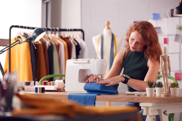 istock Female Student Or Business Owner Working In Fashion Using Sewing Machine In Studio 1307384909