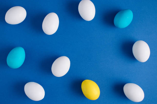 istock Yellow, white and light blue eggs on a blue background. Minimal Easter or food layout. Creative holiday concept. Flat lay 1307385943