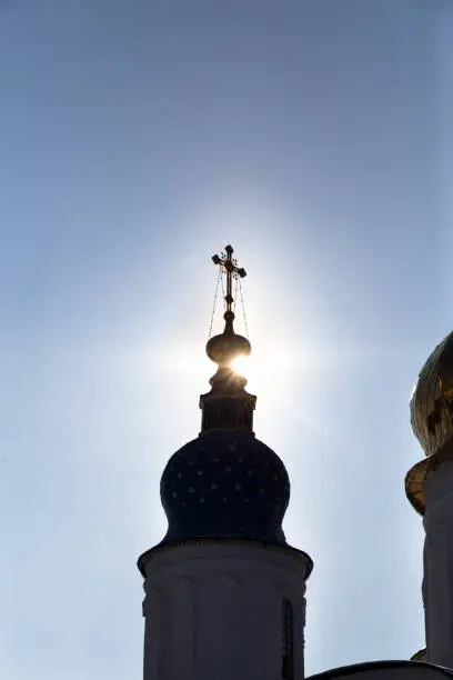 Orthodox cross on the tower of the church. Sun contour light