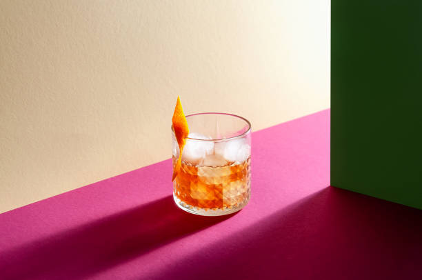 Glass with Whiskey and Ice Cube on Table with Hard Shadows. Modern Isometric Style. Creative Concept Glass with Whiskey and Ice Cube on Table with Hard Shadows. Modern Isometric Style. Creative Concept. brandy photos stock pictures, royalty-free photos & images