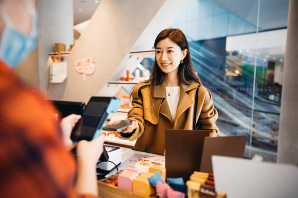 Asian businesswomen paying with smartphone. Japan, China - East Asia, Singapore, QR Code, Chinese Ethnicity, Mobile Payment shopping asia stock pictures, royalty-free photos & images