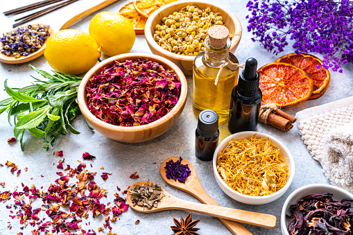 Aromatherapy and herbal medicine: group of dried herbal tea leaves, flower petals, essential oils, massage oils, dried orange slices, cinnamon sticks, star anise, herbs, and incense sticks arranged on a table. High resolution 42Mp studio digital capture taken with SONY A7rII and Zeiss Batis 40mm F2.0 CF lens