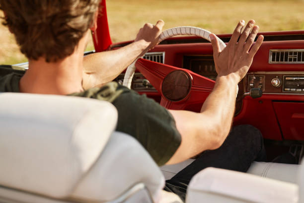 istock Rear view of man driving a red old car 1307390254