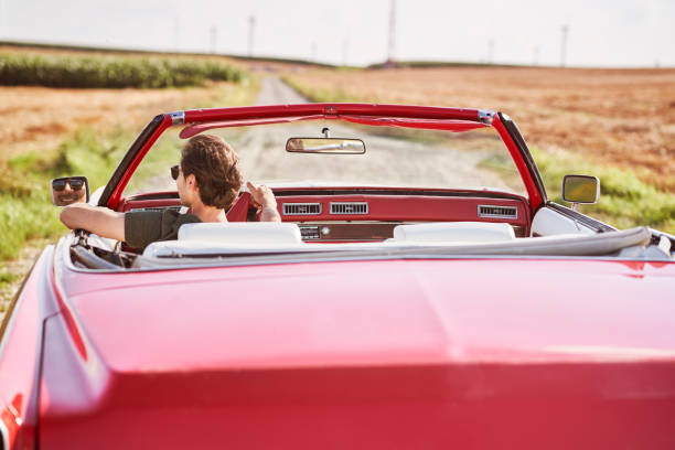 istock Smiling  man driving a red old car 1307391600