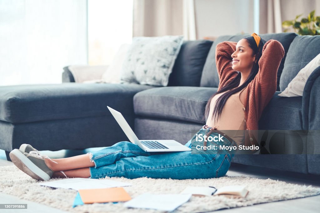 To live your best, find your balance Shot of a young woman relaxing while working in the living room at home Savings Stock Photo
