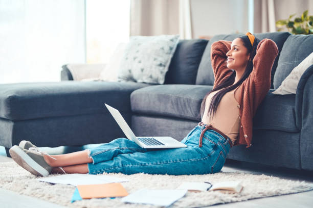To live your best, find your balance Shot of a young woman relaxing while working in the living room at home home finances stock pictures, royalty-free photos & images