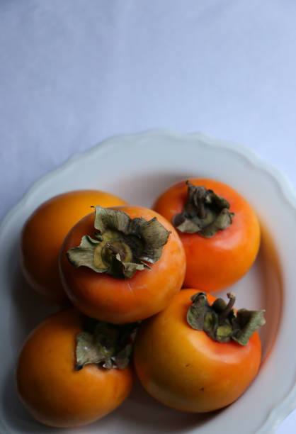 istock Fresh Ripe Persimmons on a White Classic Design Plate, Paradise Palms 1307392583