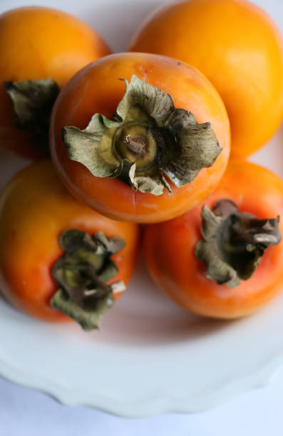istock Fresh Ripe Persimmons on a White Classic Design Plate, Paradise Palms 1307392618