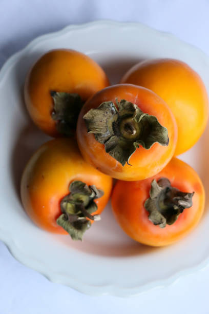 istock Fresh Ripe Persimmons on a White Classic Design Plate, Paradise Palms 1307392649