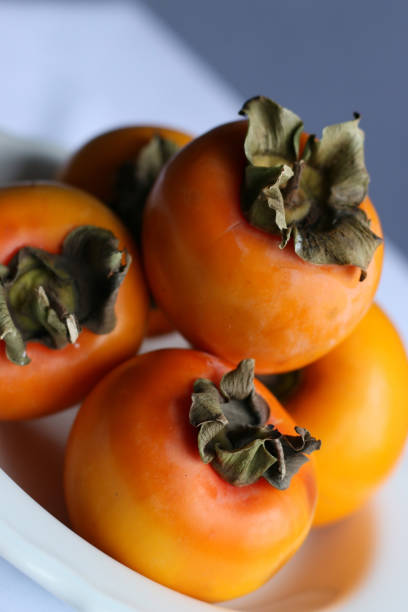 istock Fresh Ripe Persimmons on a White Classic Design Plate, Paradise Palms 1307392723