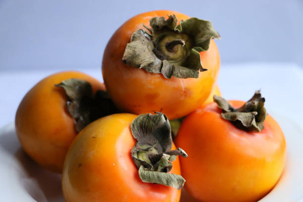 istock Fresh Ripe Persimmons on a White Classic Design Plate, Paradise Palms 1307392752
