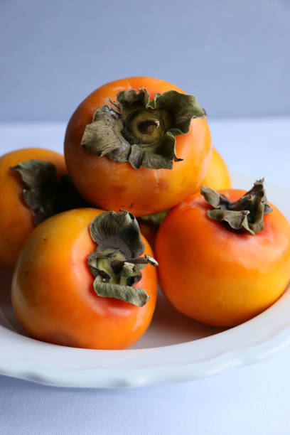 istock Fresh Ripe Persimmons on a White Classic Design Plate, Paradise Palms 1307392809