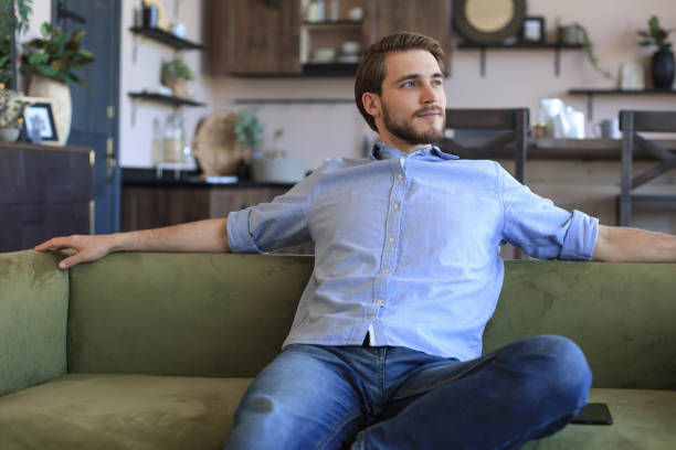 istock Handsome young business man is looking relaxed while sitting on the couch at home. 1307392825