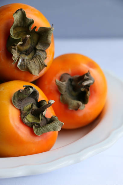 istock Fresh Ripe Persimmons on a White Classic Design Plate, Paradise Palms 1307392875