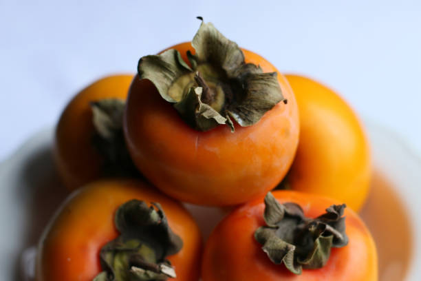 istock Fresh Ripe Persimmons on a White Classic Design Plate, Paradise Palms 1307392898
