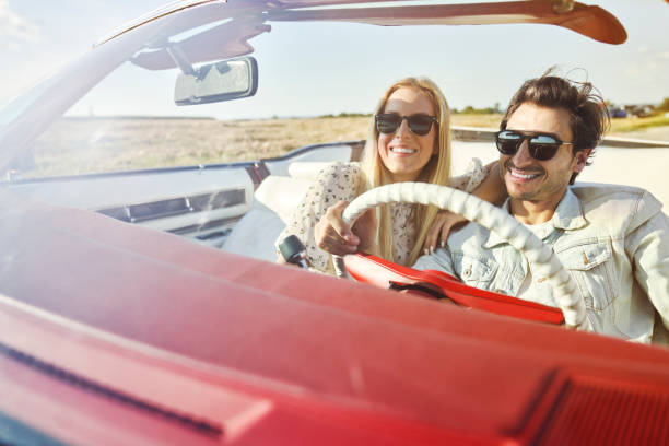 istock Smiling couple while driving freedom in convertible 1307392930