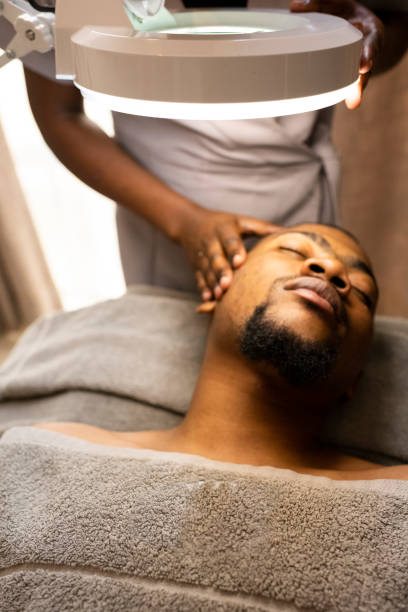 Man receives facial treatment at beauty spa Man receives facial treatment at beauty spa black male massage stock pictures, royalty-free photos & images