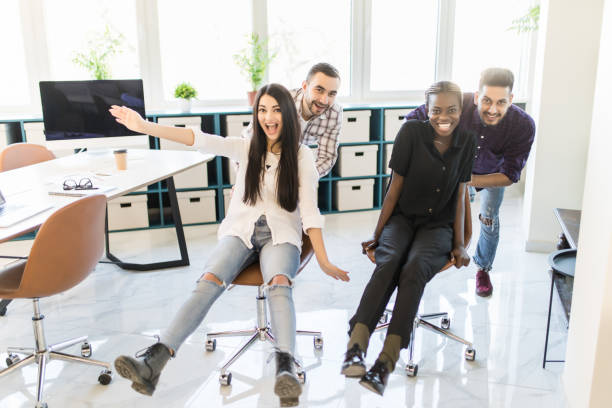 istock Happy multiracial colleagues group having fun together, riding on chairs in office, diverse excited office workers enjoying break, laughing, engaged funny activity, celebrating corporate success 1307398522
