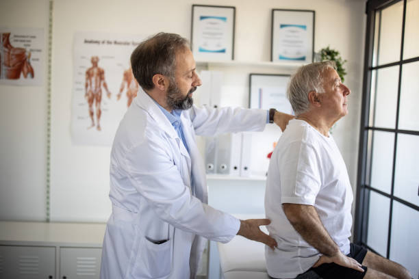 Physical therapist examining senior patient's back injury at doctor's office Physical therapist examining senior patient's back injury at doctor's office back pain stock pictures, royalty-free photos & images