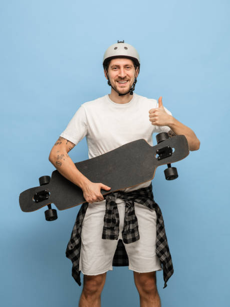 istock Happy athletic man skateboarder with longboard isolated on blue background 1307398795