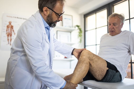 Doctor examining patient's leg injury at doctor's office