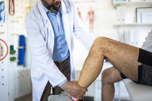 Physiotherapist checks range of motion of patient's leg at doctor's office