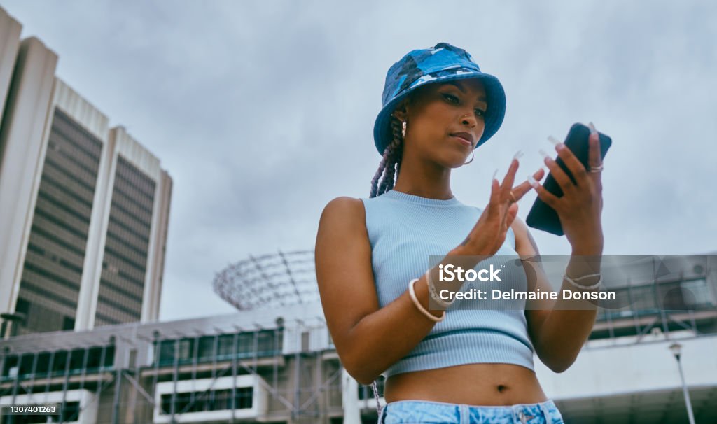Every city has a social media queen Shot of a trendy young woman using a smartphone against an urban background Cool Attitude Stock Photo
