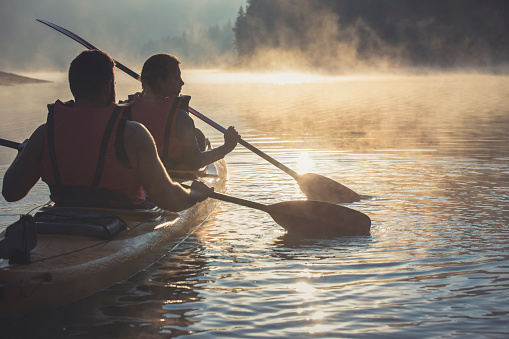 A shot of young couple exploring mountain lake with kayak in the morning.