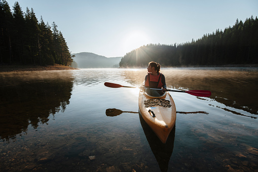 A front view of a woman kayaking and exploring mountain lake.
