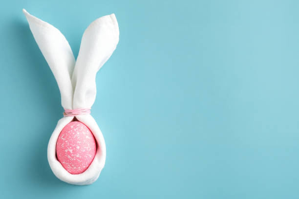 istock Easter bunny made of napkin and pink egg on turquoise background. Minimal style. Easter card template. 1307402621