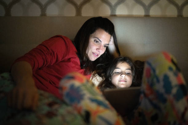 istock Mother and daughter in bed watching something on digital tablet 1307403034