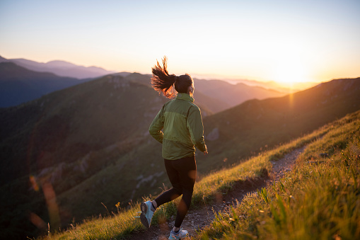 Young fit woman with all running eqipment running in the high mountain at sunset.