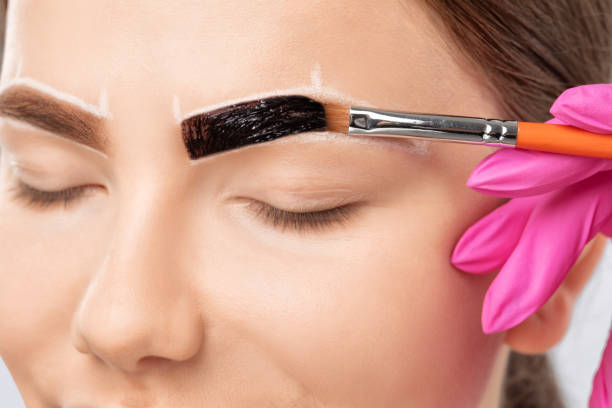istock Make-up artist makes markings with white pencil for eyebrow and paints eyebrows. Professional makeup and facial care. 1307406621