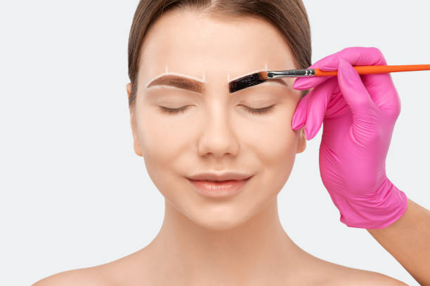 istock Make-up artist makes markings with white pencil for eyebrow and paints eyebrows. Professional makeup and facial care. 1307406674