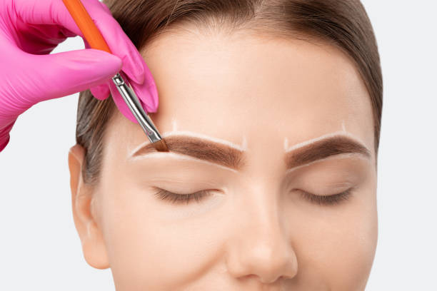 istock Make-up artist makes markings with white pencil for eyebrow and paints eyebrows. Professional makeup and facial care. 1307406705