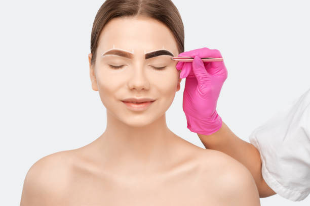 istock Make-up artist makes markings with white pencil for eyebrow and paints eyebrows. Professional makeup and facial care. 1307406713