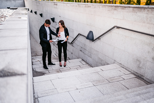 Young handsome business man and woman discussing work on the go.