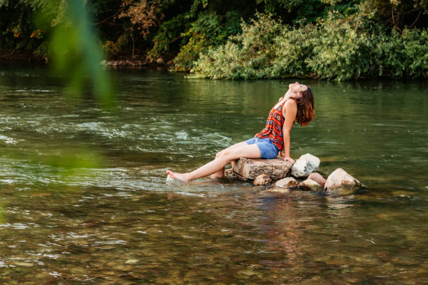istock Woman sitting on a stone in the river 1307409459