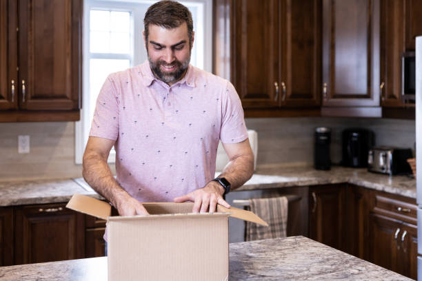 istock Happy Man Receiving and Opening a Packgage at Home 1307409607