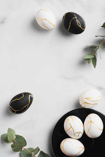 istock Elegant white and black Easter eggs decorated gold and eucalyptus leaves on marble table. Flat lay, top view, vertical. 1307409923
