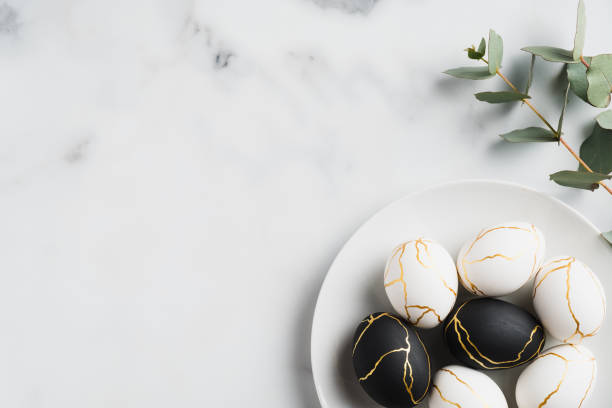 istock Luxury white and black Easter eggs decorated gold and eucalyptus leaves on marble table. Happy Easter card. Flat lay, top view, copy space. 1307409925