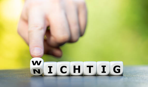 hand turns dice and changes the german word "nichtig" (unimportant) to "wichtig" (important). - wichtig imagens e fotografias de stock