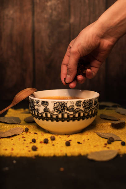 istock Cook hand adding spice to vegetarian tomato soup in bowl at home or restaurant 1307411432